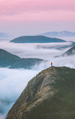 S=Person standing on a moutain with loads of mist