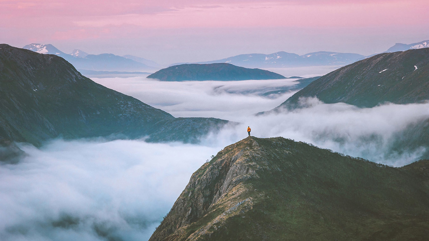 Person standing on a mountain with mist surrounding